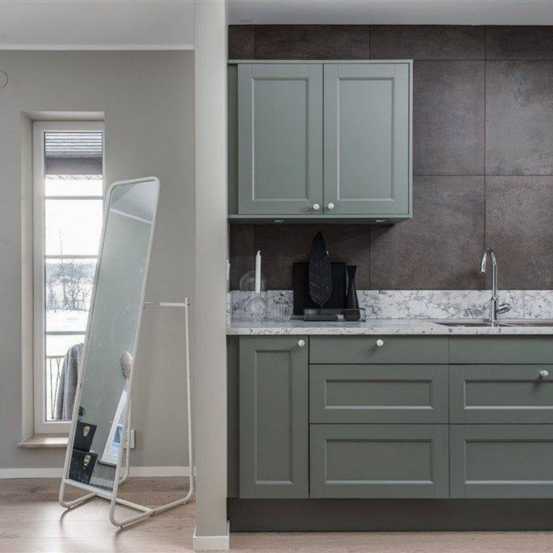 Kök med grågröna skåp, stora bruna väggplattor och vit marmordetaljer, en köksrenovering som visar elegans i enkel design.