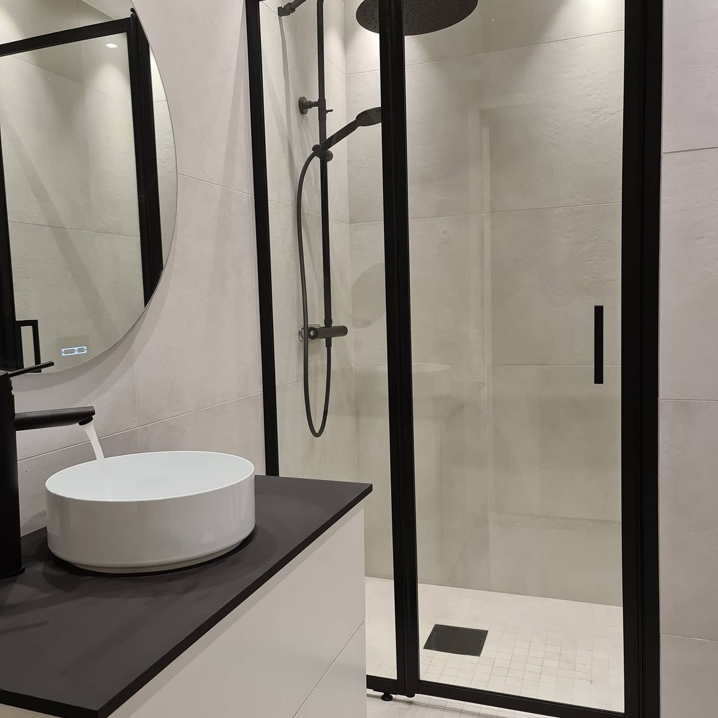 Helkaklat badrum med duschvägg i glas och svart duschset – badrumsrenovering Norrköping