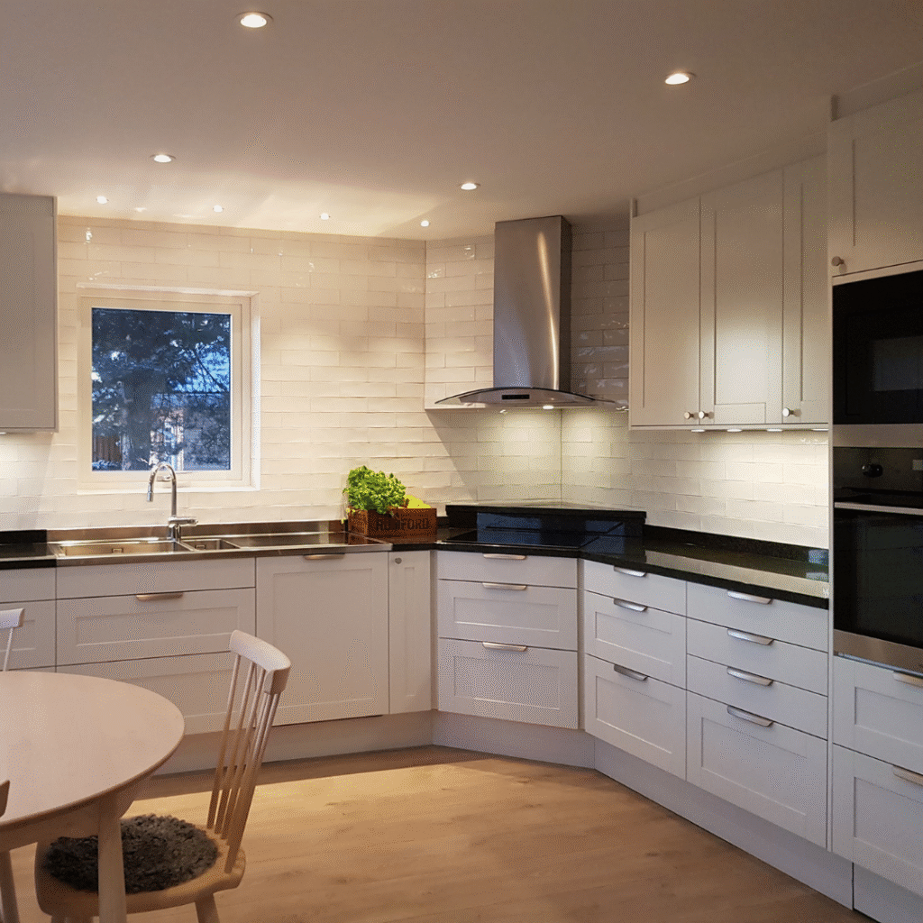 Stort vitt kök med hörnlösning, spotlights och rostfri köksfläkt, en professionell köksrenovering som ger både ljus och rymd.