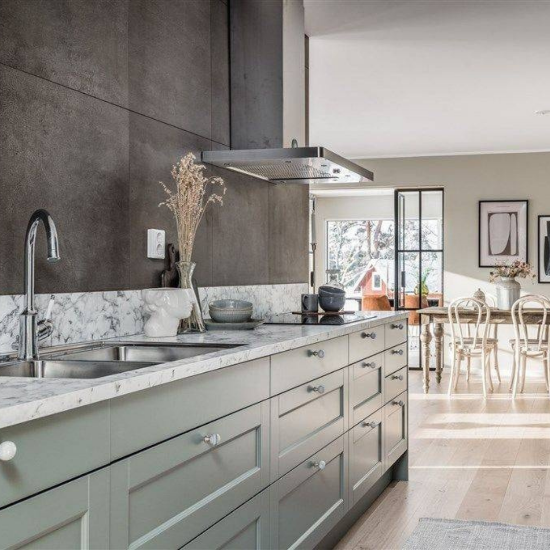 Modernt kök i grågrön ton med marmorinspirerad bänkskiva och integrerad spis, ett exempel på stilren köksrenovering som kombinerar funktion med estetik.