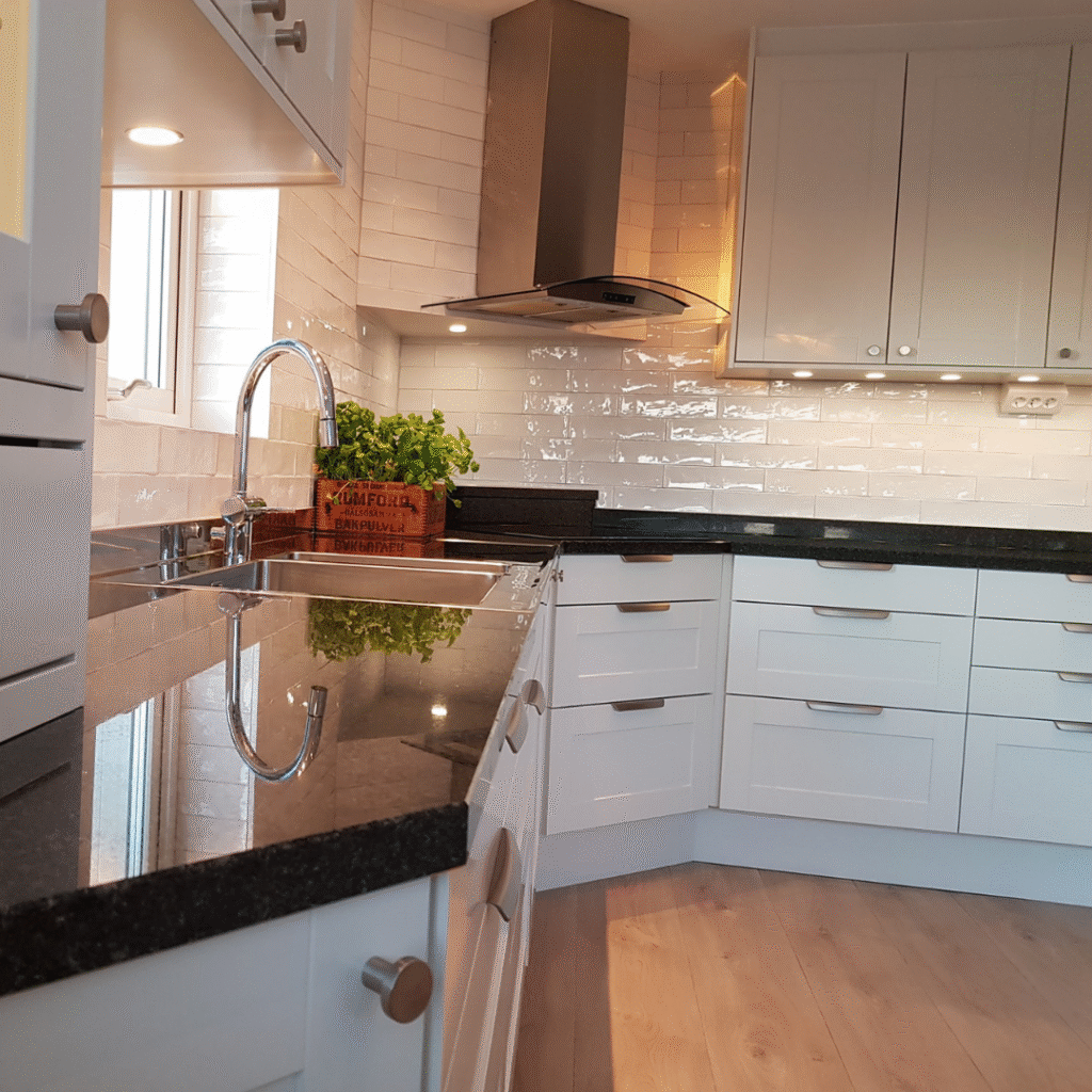 Ljust kök med vita luckor, svart bänkskiva och blanka vita kakelplattor, ett fräscht exempel på köksrenovering med klassisk känsla.