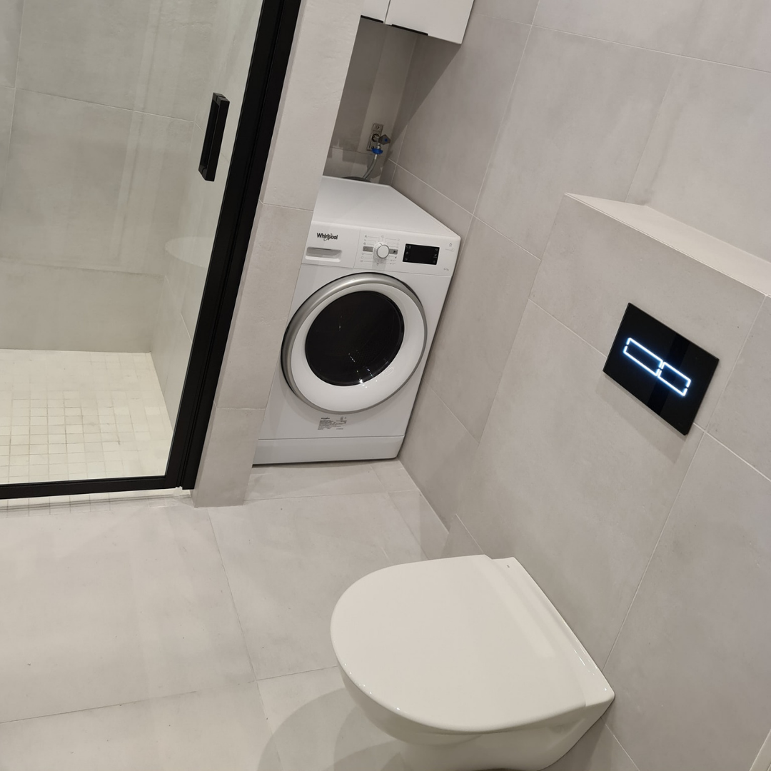 Ljust badrum med tvättmaskin och toalett i samma rum – praktisk badrumsrenovering i Norrköping